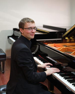 Young smiling musician at Grand piano